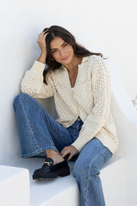 Cloud Dancer Crochet Cardigan natural cream – model sitting outdoors