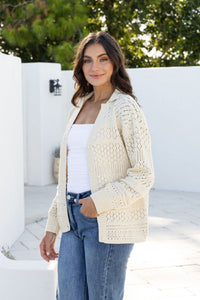 Cloud Dancer Crochet Cardigan natural cream – model with cardigan open and hand in pocket of blue jeans