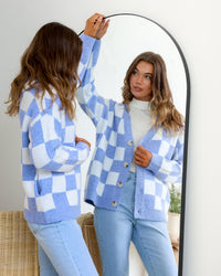 Monti Checker Knit Cardi powder blue and white by Miss Marlow – model looking in mirror styled with light blue jeans