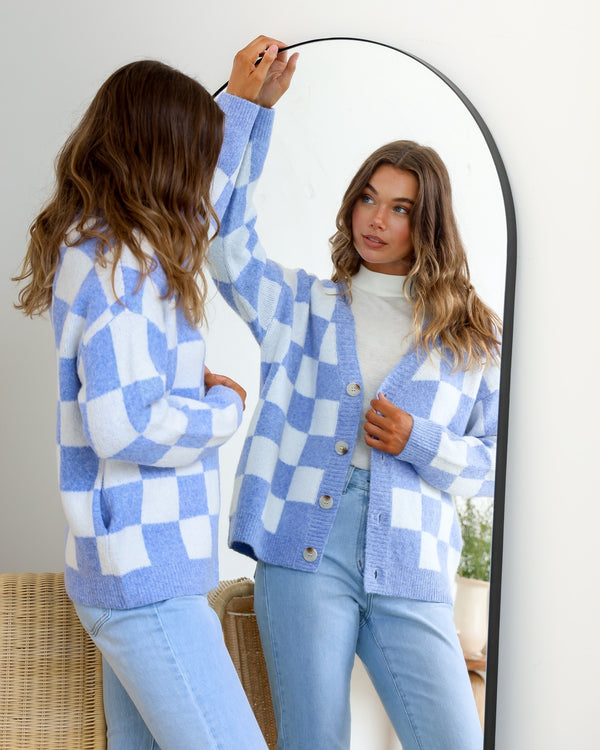 Monti Checker Knit Cardi powder blue and white by Miss Marlow – model looking in mirror styled with light blue jeans
