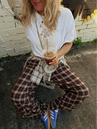 Jaase Stevie Austin Flannel Pants chocolate – outdoor lifestyle shot with model sitting holding iced coffee