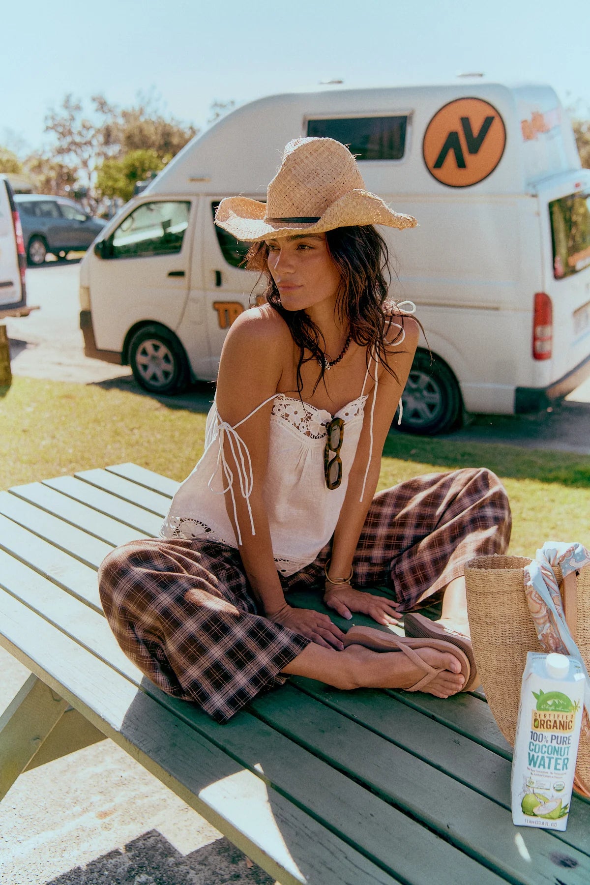 Jaase Stevie Austin Flannel Pants chocolate by Jaase – model sitting on beach park bench cowboy hat and white cami top with thongs outdoor lifestyle shot